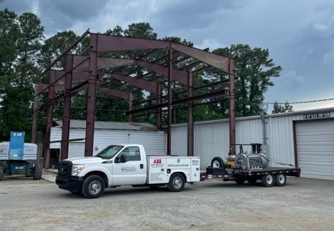 729c15_03099727cf4d426ba7d194fb0c27d71f~mv2 An exterior photograph of Rocky Mount Electric Motor with one of their trucks pulling an electric motor on a trailer.