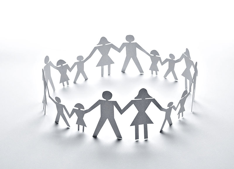 A stock graphic of paper cutout people holding hands in a circle.