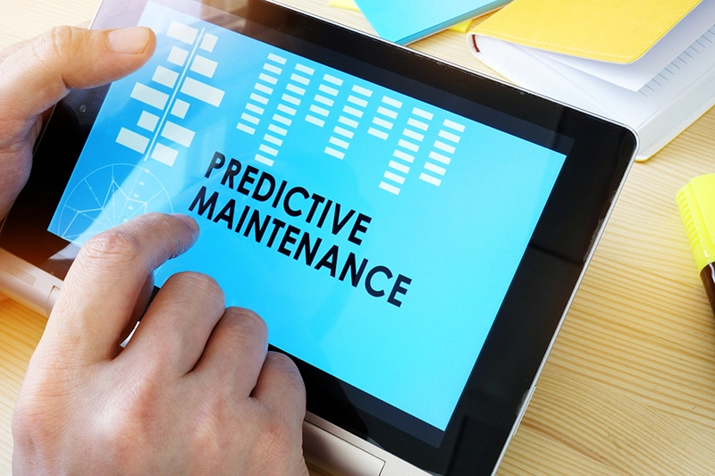 A stock photo of hands holding a tablet that has the message "Predictive Maintenance" displayed on it.