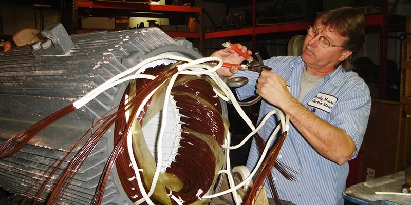 Timmy making connections A middle aged mechanic connects cables together while performing electric motor rewinding.