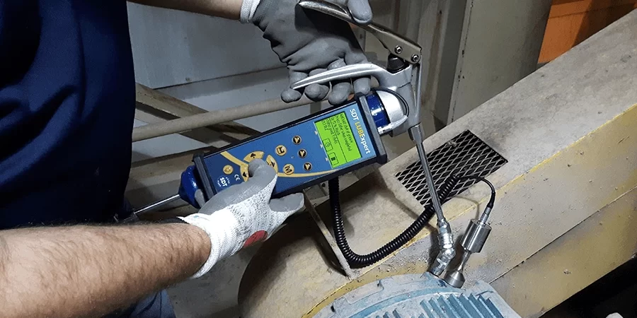 accu-lube A man performs predictive maintenance by using a lubrication tool to ensure electric motor lubrication is done correctly.