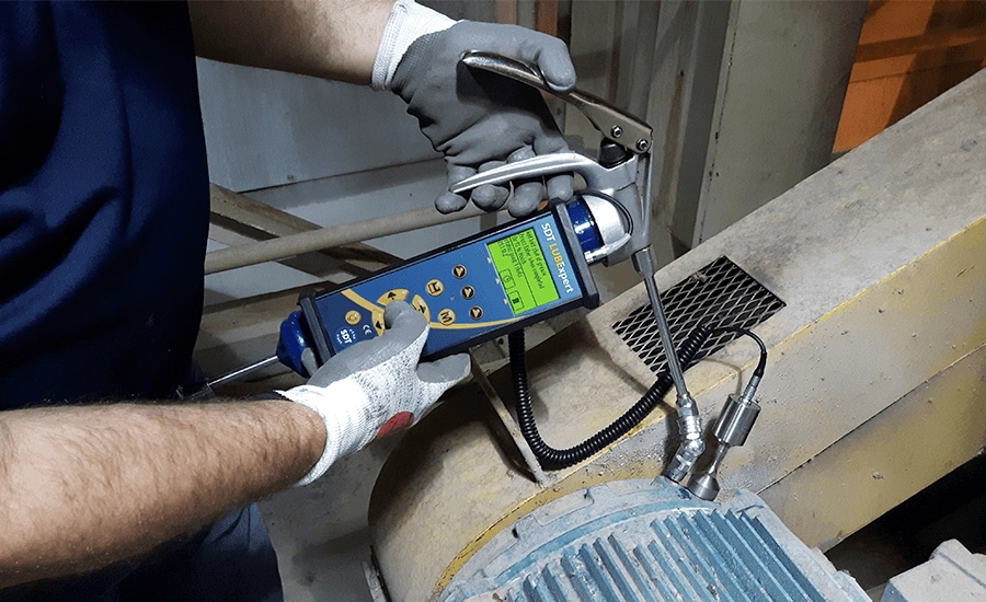 accu-lube A man performs predictive maintenance by using a lubrication tool to ensure electric motor lubrication is done correctly.