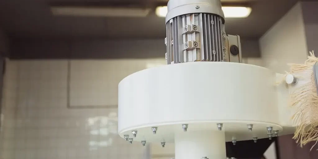 industrial-electric-motor-to-drive-the-fan-in-cycl-2023-11-27-05-12-52-utc-min An industrial electric motor sits upright atop a large, white metal industrial installation.