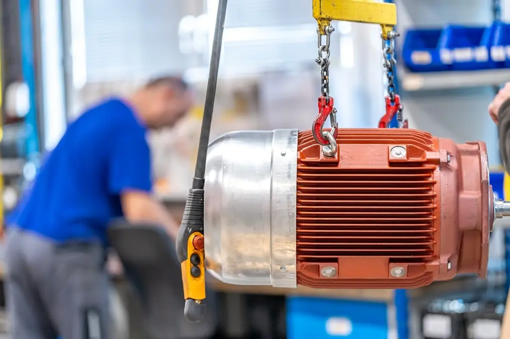 An electric motor hung on a production line in a workshop.