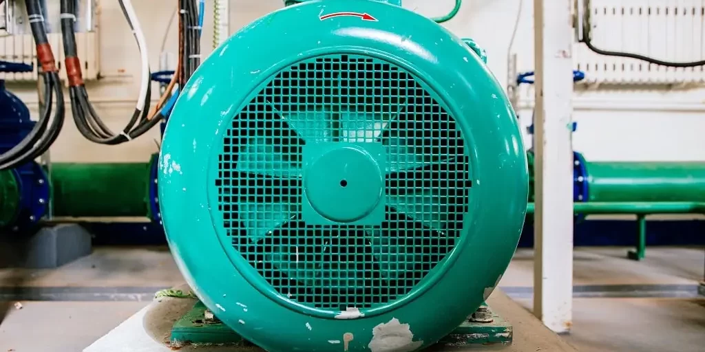 different-equipment-at-the-compressor-station-at-t-2023-11-27-05-36-47-utc-min The front face of an industrial electric motor in a maintenance tunnel.