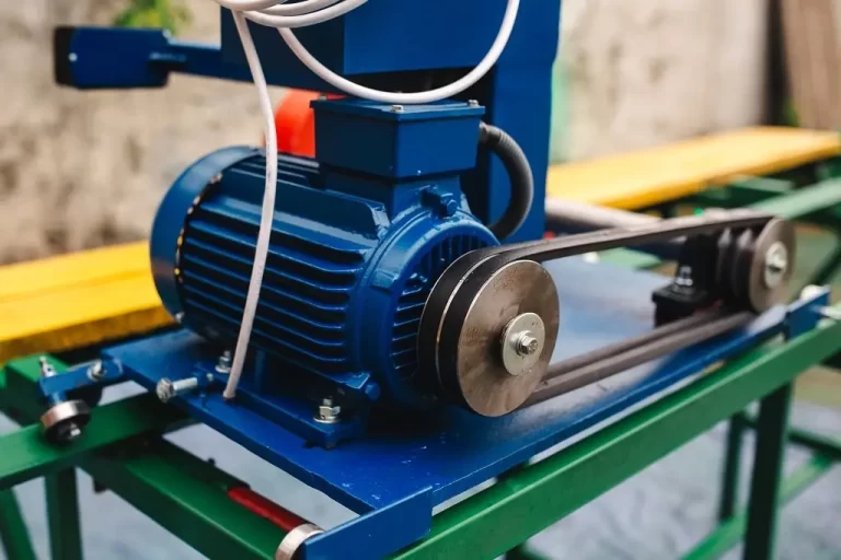 Closeup of an electric motor attached to a pulley on a circular saw wood cutting machine.
