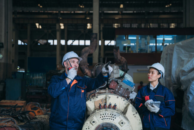 Team engineers are on duty and talking, looking at, and repairing the big machine in the railroad garage. Team engineers are on duty and talking, looking at, and repairing the big machine in the garage.