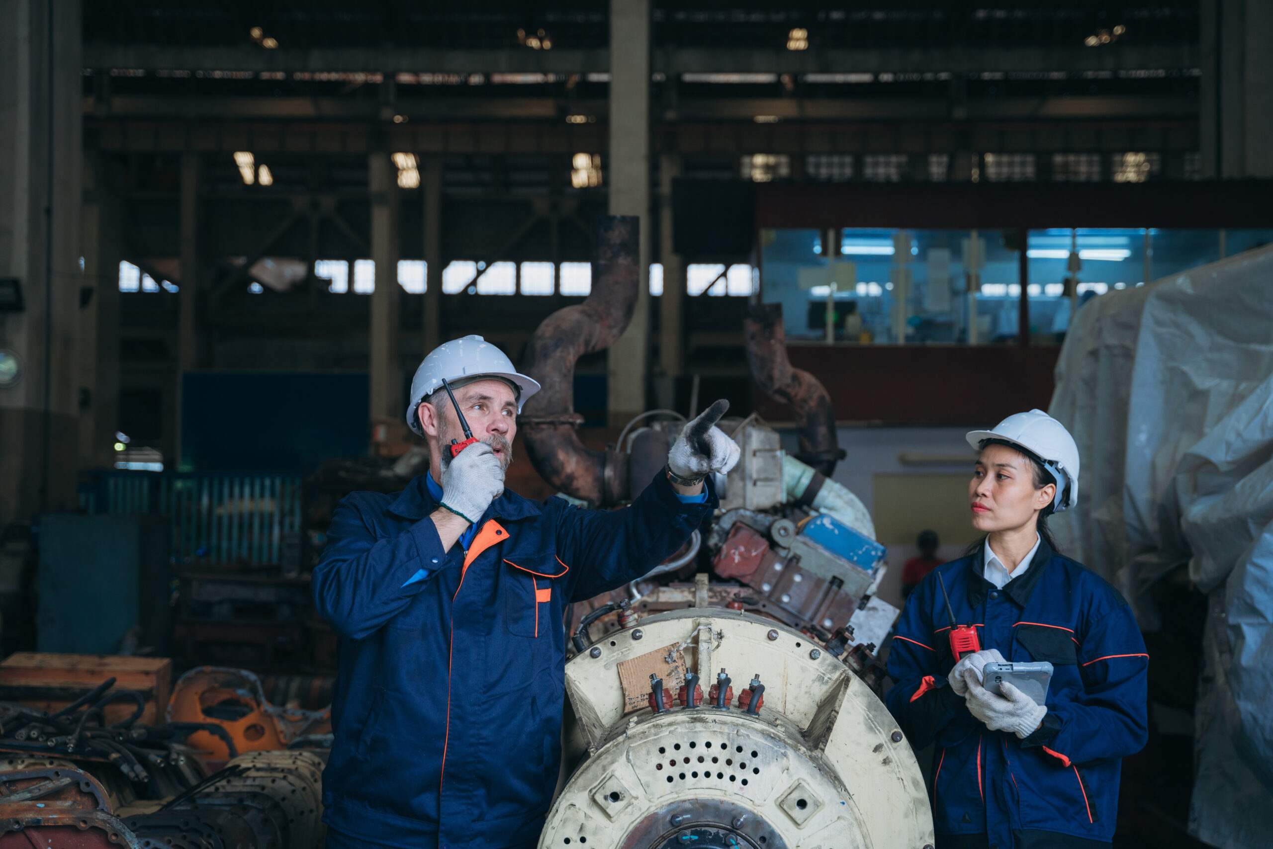Team engineers are on duty and talking, looking at, and repairing the big machine in the railroad garage. Team engineers are on duty and talking, looking at, and repairing the big machine in the garage.
