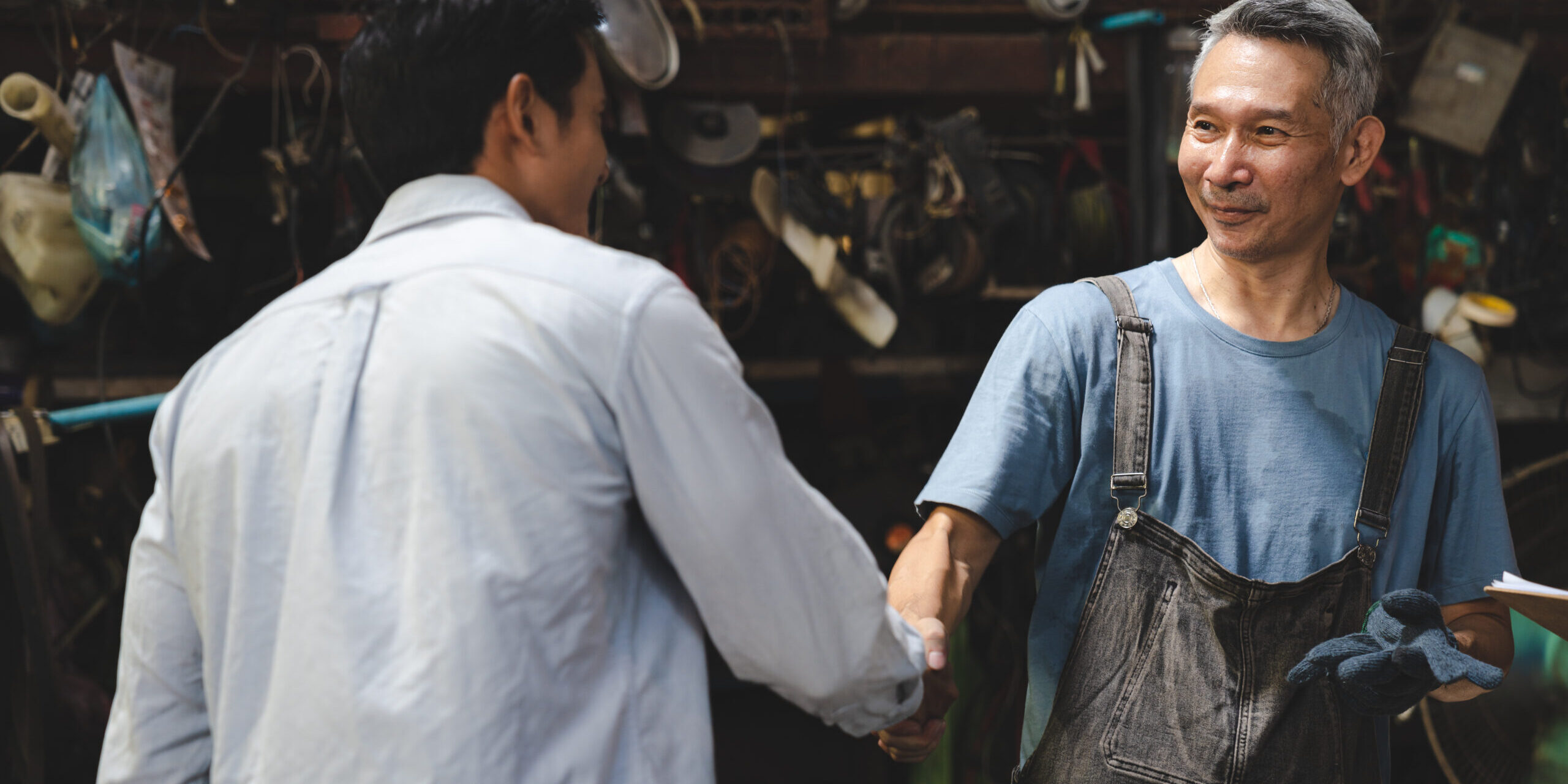 Mechanic technician man shaking hands with customer after finish checking the car at the garage, two people handshake for a working job at professional repair service center