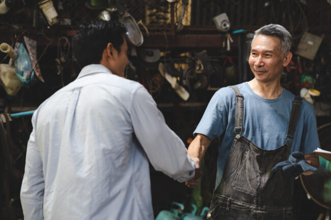 Mechanic technician man shaking hands with customer after finish checking the car at the garage, two people handshake for a working job at professional repair service center